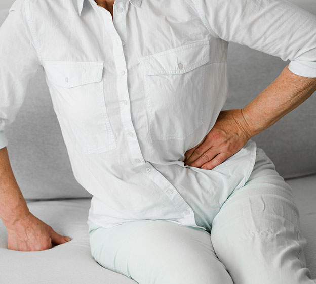 A person wearing a white shirt and white pants holding their hip