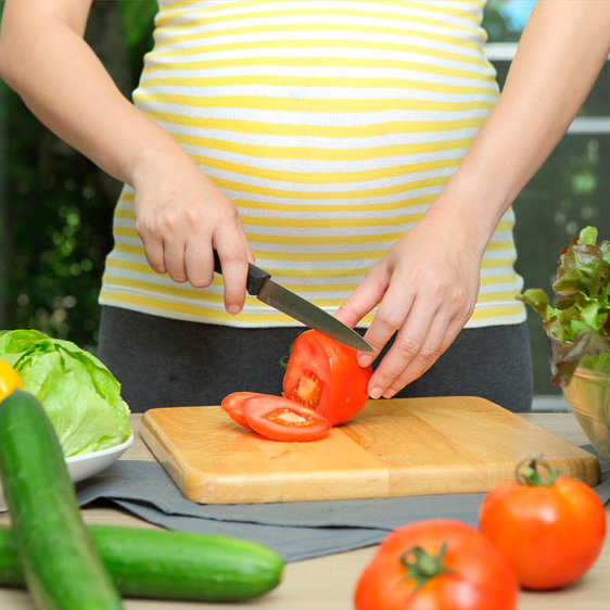 Pregnant woman chopping produce