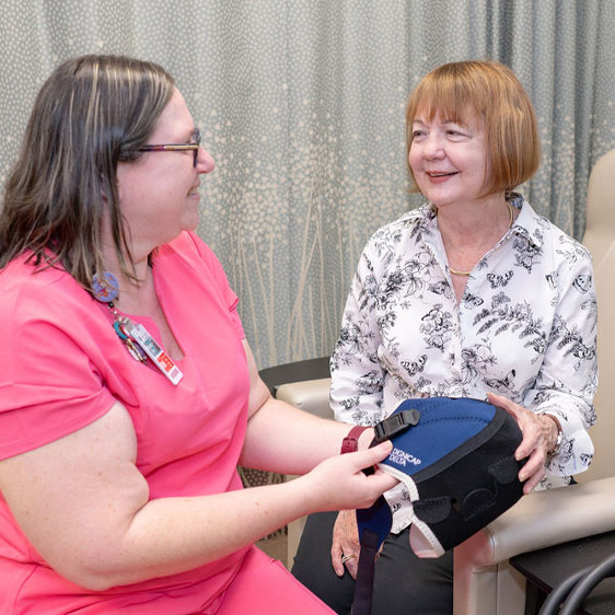 A woman named Terry Murray smiling at the camera and sitting, talking with another woman named Brandie Gillian, RN