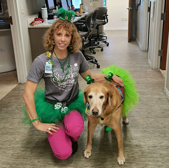 Sarah Pergande, mammographer at the Beaufort Memorial Breast Health Center, kneels next to Bella. Both are wearing green tutus in honor of St. Patrick’s day.