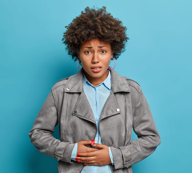 Young Black woman with a worried look on her face holding her stomach