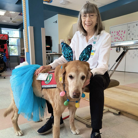Sunday sits in a chair and poses for an Easter photo with Bella, who’s wearing an aqua blue tutu and sparkly bunny ears.