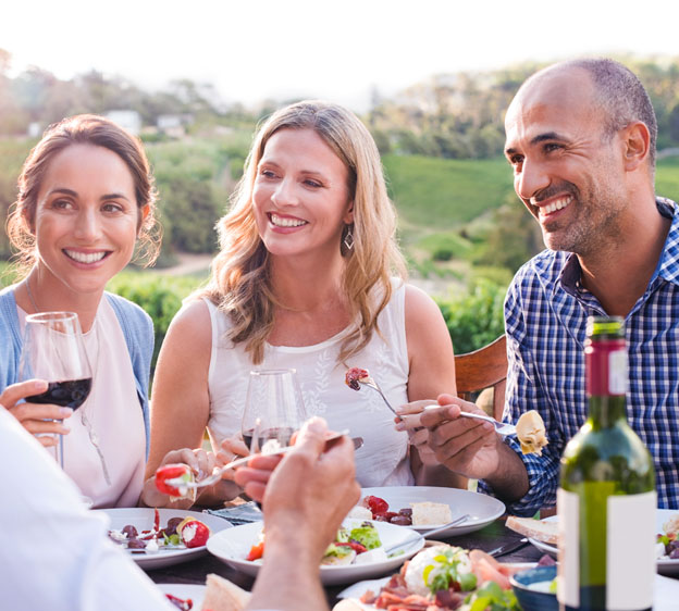 friends enjoying a meal with vegetables and wine