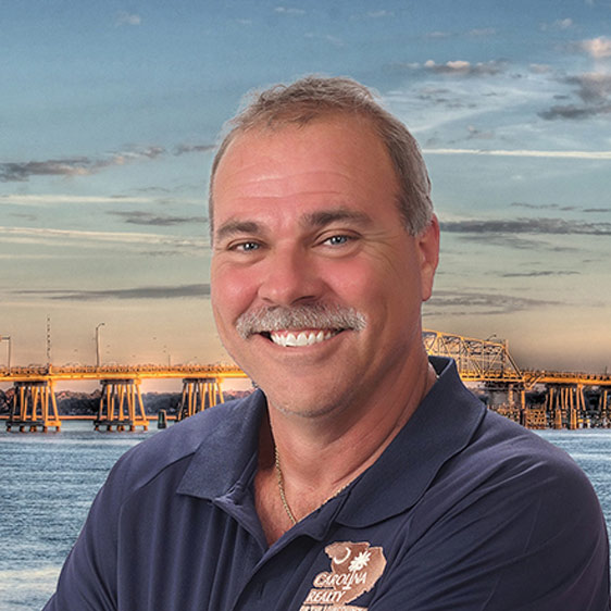 John Aust smiling at the camera with the sea behind him