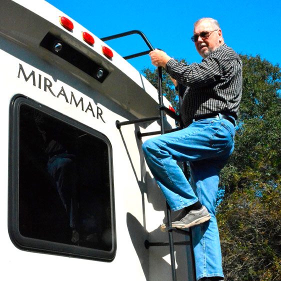 Larry Cook climbs a ladder to the top of his RV.