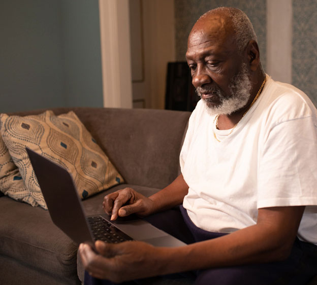 Older Black man sitting on a couch having a telehealth visit