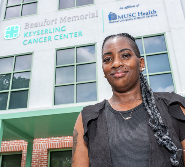 Breast cancer survivor Claudia Holmes smiles in front of the Keyserling Cancer Center