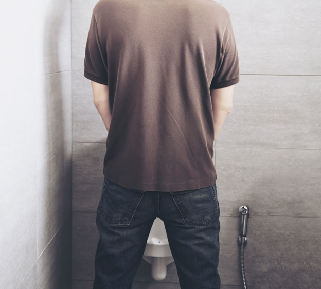 Man standing in front of a urinal with his back to the camera