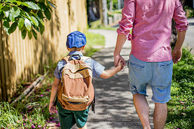 child with backpack walking with parent