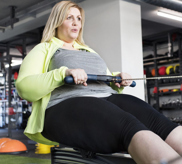overweight woman using a rowing machine