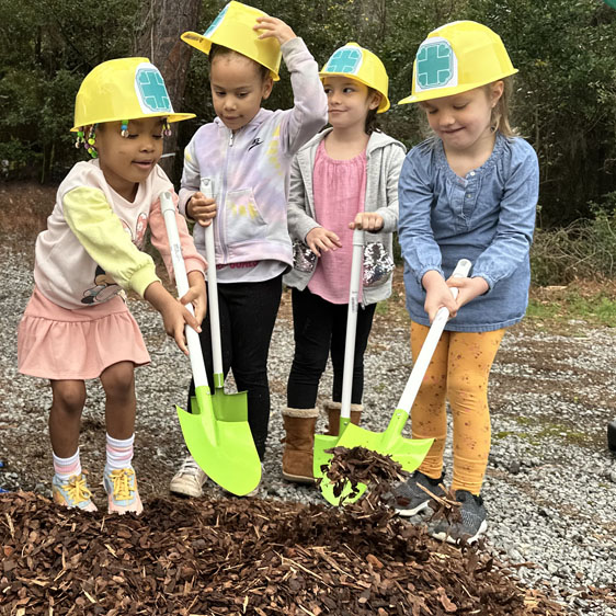 A group of children hold shovels and smile