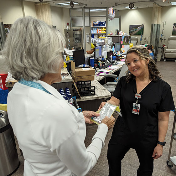 A medical professional smiles and hands a volunteer a blood sample to deliver to the lab
