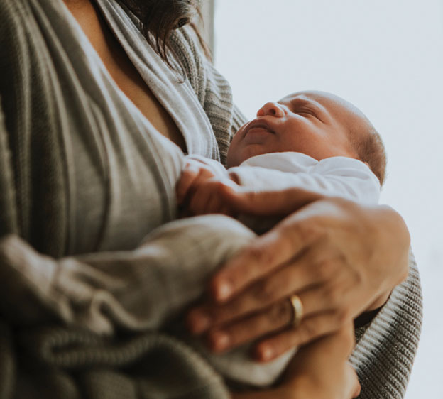 A small infant being held in someone’s arms