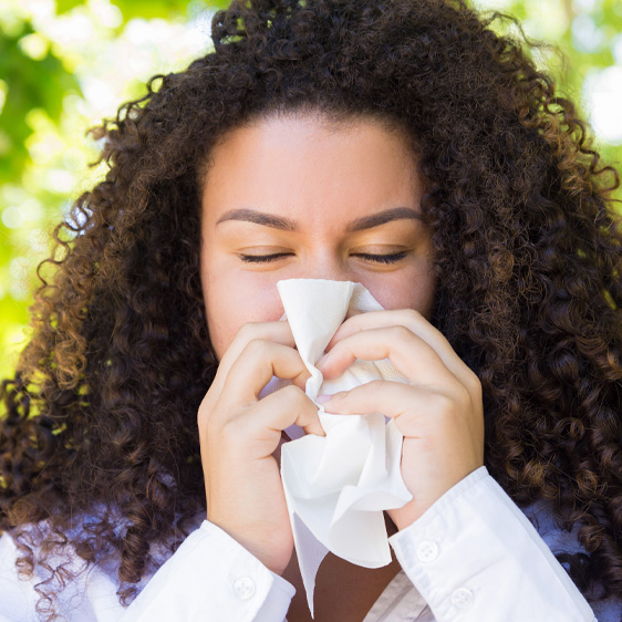 Woman blowing her nose and suffering from seasonal allergies