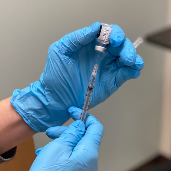 health care worker filling a syringe